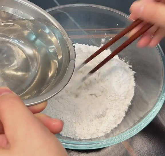 Gradually pour boiled water into the dry mixture while stirring continuously with chopsticks
