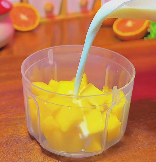 add half of the mango cubes (250g) and 250ml coconut milk