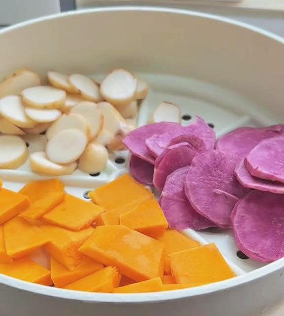 place the peeled and sliced pumpkin, purple potato, and taro in the steamer basket