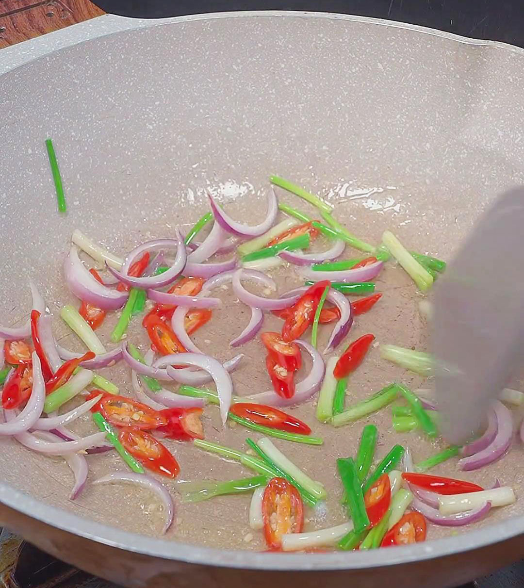 Stir fry the chopped red onions, chopped green onions, and Thai chili pepper