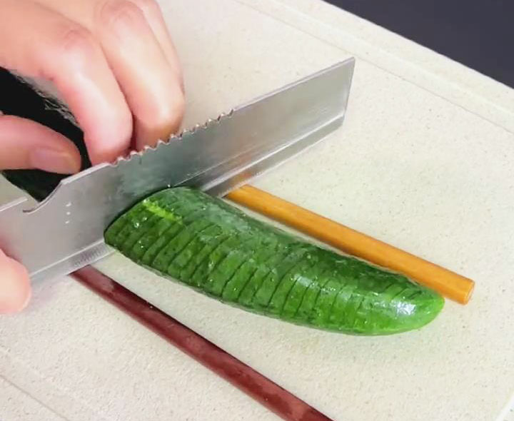 Flip the cucumber to the other side and cut it into diagonal slices while the chopsticks are still on each side