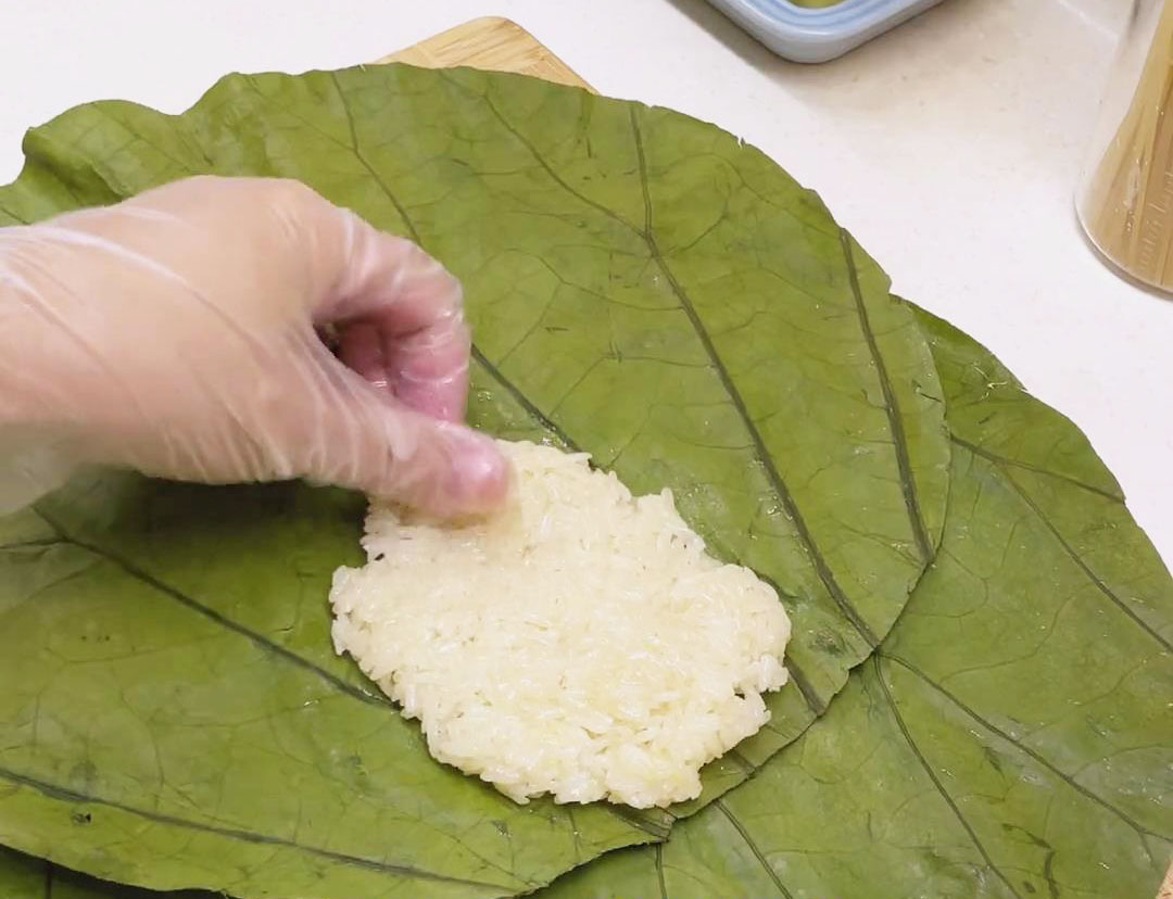 Place the flattened glutinous rice on 2 pieces of lotus leaves