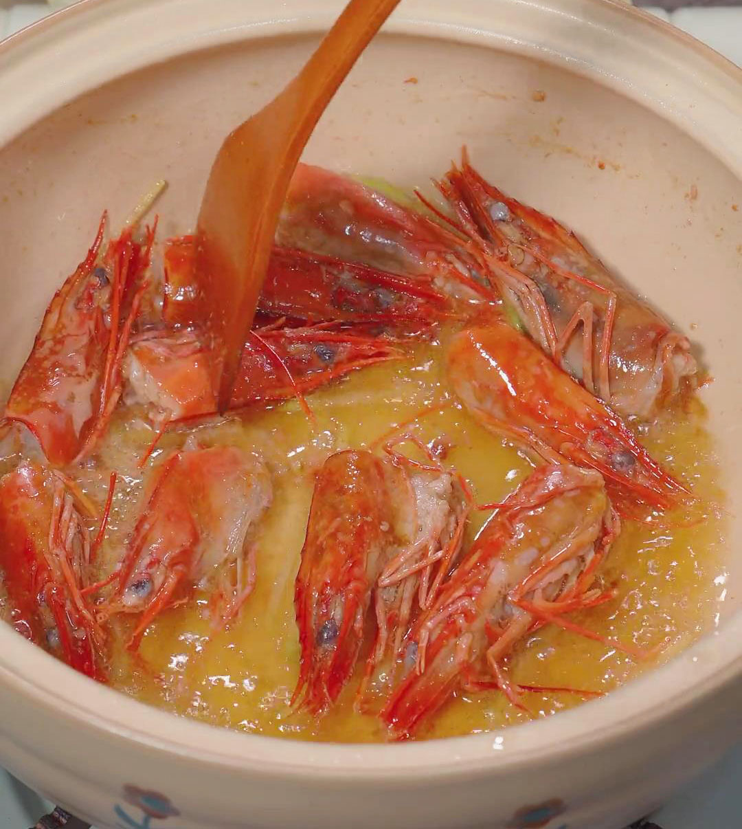 In a pot, heat oil and fry shrimp heads and sliced ginger