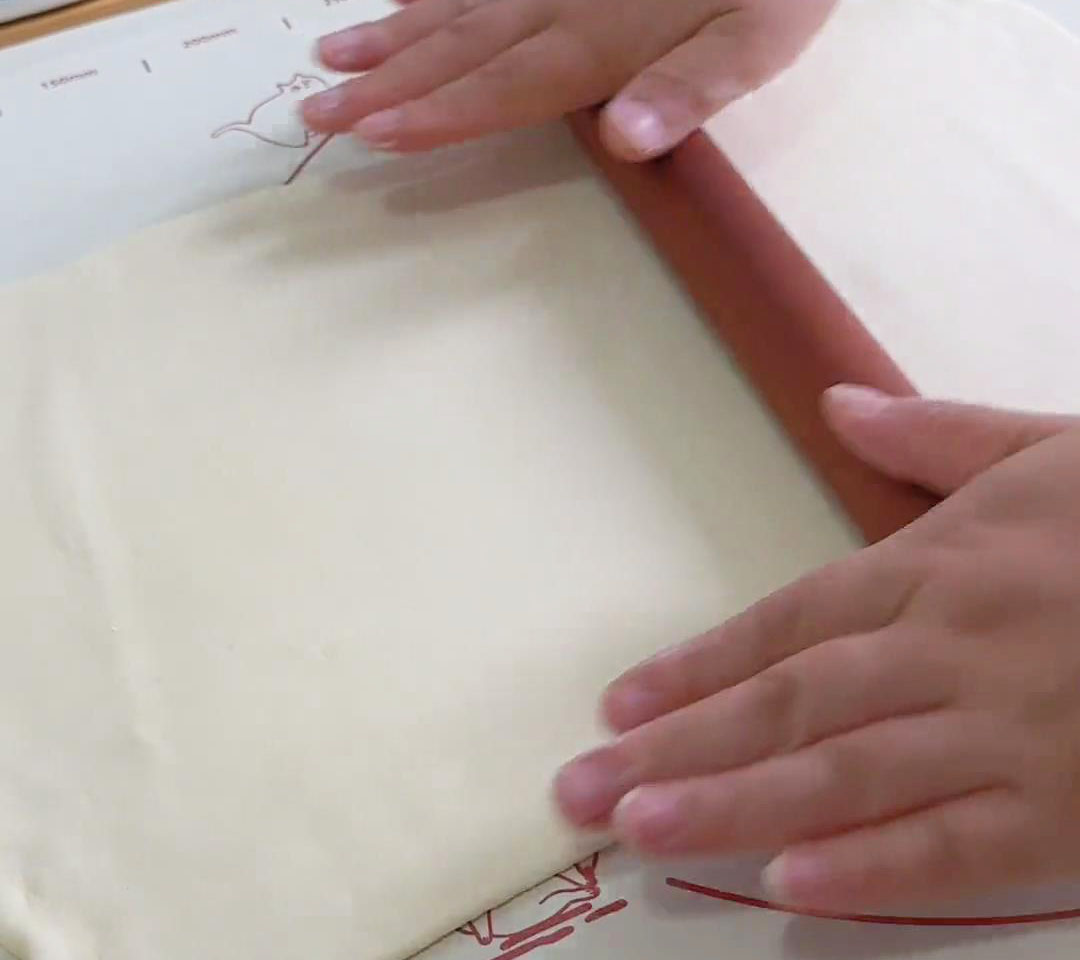 Roll the dough out into a large rectangular sheet using a rolling pin