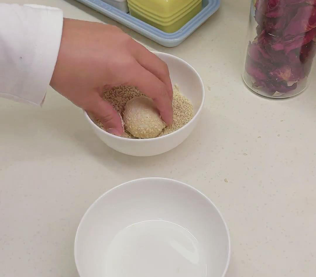 Coat the sesame ball by rolling it in the mixture