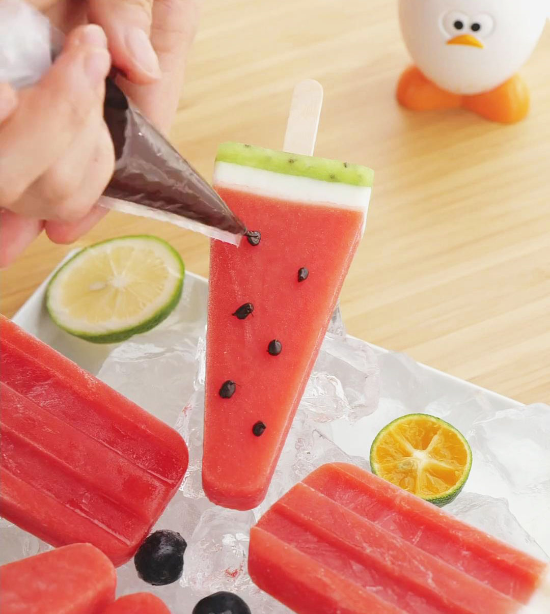 Decorate the watermelon popsicles with dots of chocolate to create the seeds